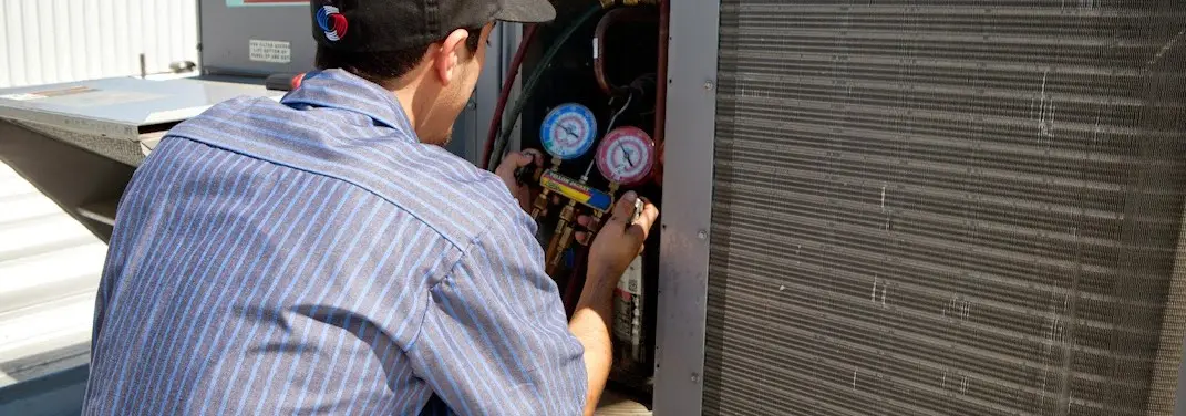 HVAC technician servicing a condenser unit in Livingston