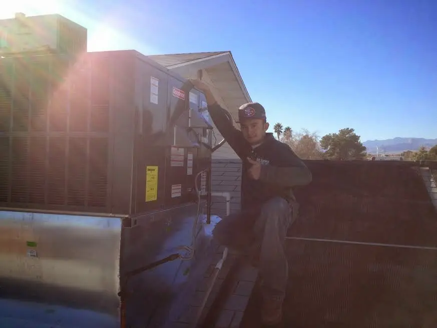 HVAC technician performing AC Tune-Up on a rooftop unit in Livingston